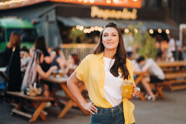 水果一个穿着黄色衬衫和短裤 喝着一杯柠檬汁的女孩站在街上柠檬鸡尾酒咖啡馆女人