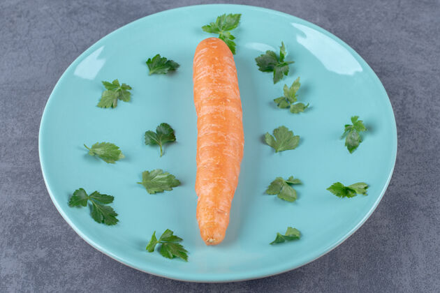 蔬菜一根胡萝卜放在盘子里 上面是绿色的 放在大理石表面上营养新鲜胡萝卜