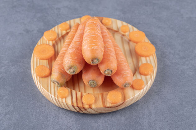 美味整个胡萝卜和切片在木板上 在大理石表面风味生的新鲜