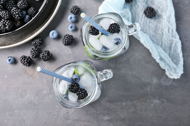 玻璃桌上的梅森罐子里放着黑莓和蓝莓 让人神清气爽浆果甜点食物