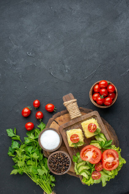 一餐切碎的新鲜蔬菜正面图切菜板上的奶酪和香料绿色捆绑在黑色表面西红柿香料胡椒