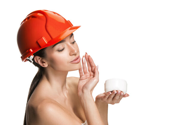 建筑戴着橙色头盔的自信的快乐微笑的女工的肖像白色工作室背景上孤立的女人美容 化妆品 护肤 皮肤和面部保护 美容和面霜概念成人工程师女孩