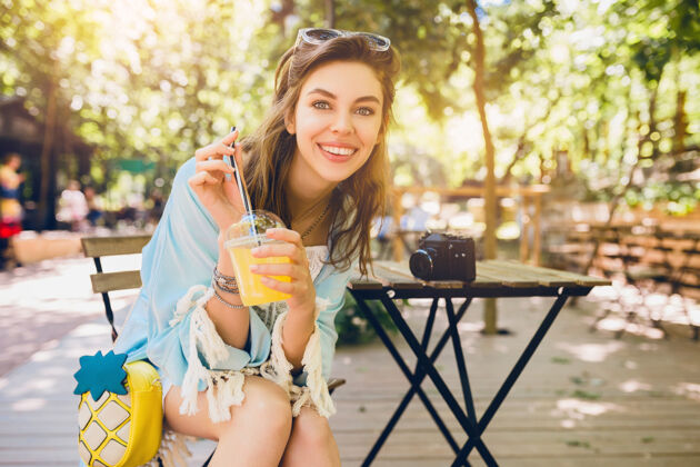 情感年轻迷人的女人坐在咖啡馆里 穿着夏天的时装果汁快乐喝酒