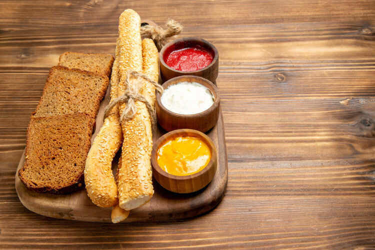 早餐正面图黑面包面包面包和调味品棕色木制餐桌上的食物面包面包面包面包辛辣面包调味品辛辣