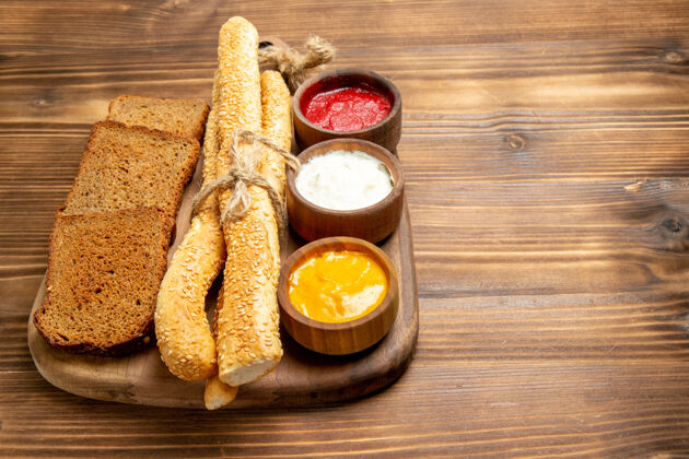 早餐正面图黑面包面包面包和调味品棕色木制餐桌上的食物面包面包面包面包辛辣面包调味品辛辣