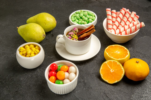 食用水果在深灰色的空间里可以看到一杯茶 里面有糖果和新鲜水果饮食柑橘茶杯