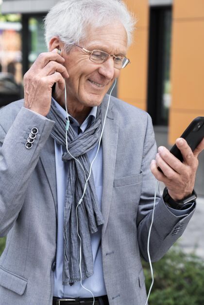 老年人时尚的老男人在城市使用智能手机和耳机的视频通话城市视频通话男人