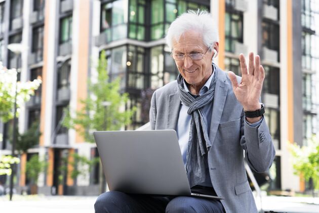 城市时尚的老男人在城市里使用笔记本电脑进行视频通话男性户外退休
