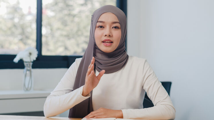 工作场所亚洲穆斯林女士在新常态办公室看摄像机和同事谈论视频通话计划伊斯兰穆斯林看摄像机