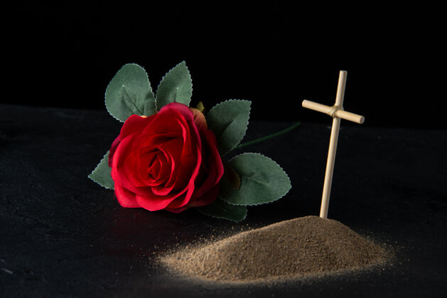 沙子从沙子上看到的小坟墓的正面图 黑色的十字架死亡花玫瑰