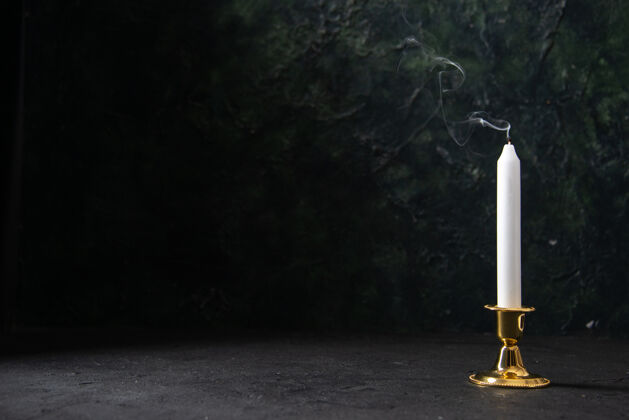 黑暗在黑色的金色的立场上白色蜡烛的正面视图光火焰火