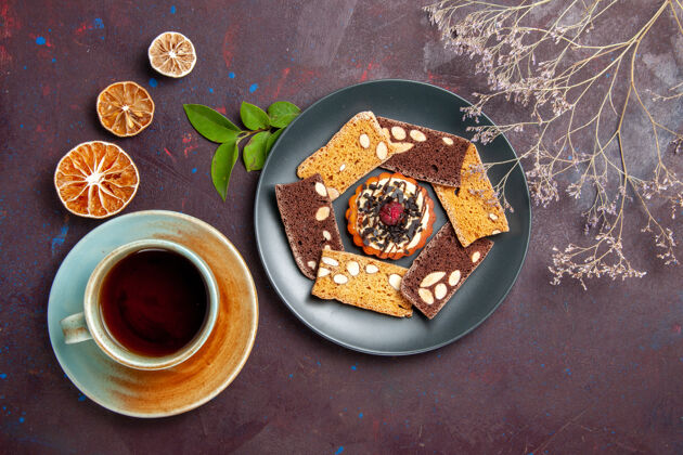 视图俯瞰美味的蛋糕片配上小饼干和一杯茶 背景为深色饼干甜点蛋糕茶甜早餐晚餐杯子