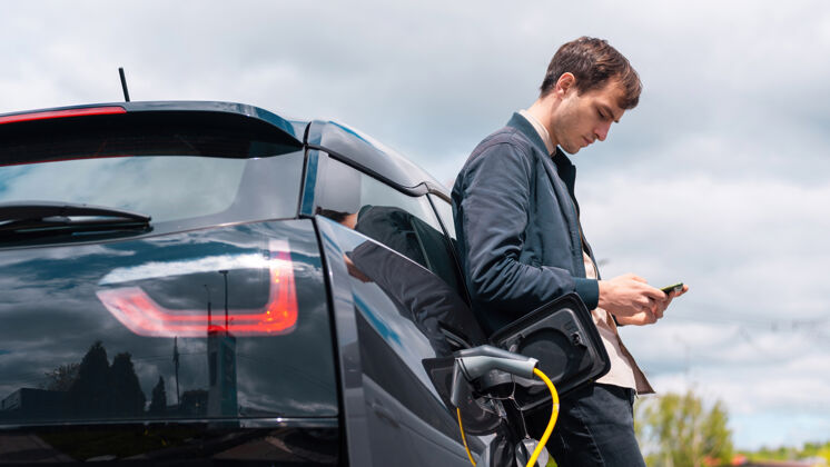 设备男人在充电站给他的电动车充电 用智能手机汽车汽车能源