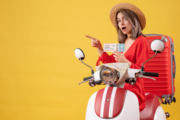 滑板车正面图：穿着红裙子的年轻女士拿着车票 用轻便摩托车指着左边持旅游旅游者