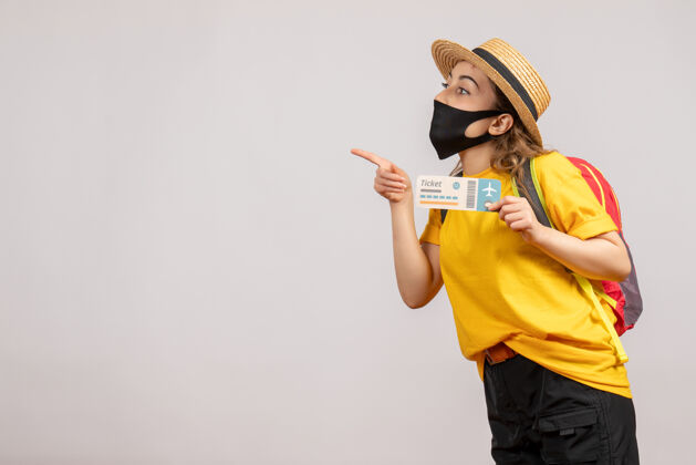旅游正面图戴着黑色面具的年轻女子拿着旅行票指着左手左旅游人