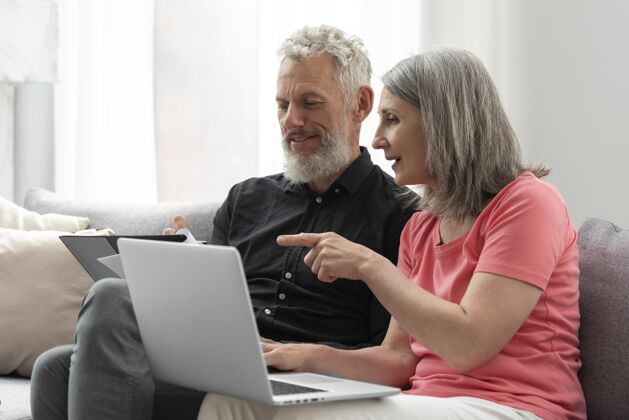 夫妇老两口在家沙发上用笔记本电脑房子设备灰色头发