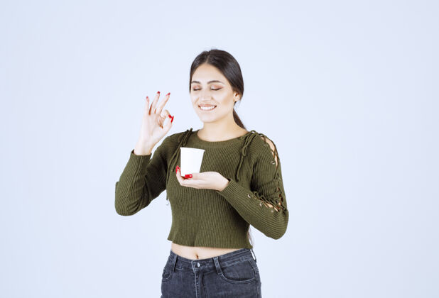 杯子年轻的黑发女子在白色背景上给喝茶的好标志休闲女士成人