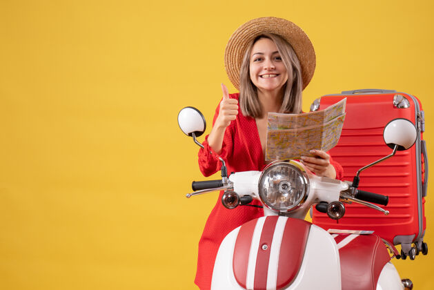女人前视图穿着红色裙子的年轻女士拿着地图在轻便摩托车旁竖起大拇指滑板车旅游摩托车