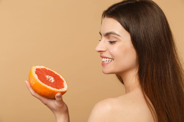 身体近景半裸体女人完美的皮肤裸妆举行葡萄柚隔离米色粉彩墙上柑橘清洁提升
