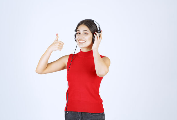 年轻穿着红衬衫的Dj戴着耳机欣赏音乐女性满意工人