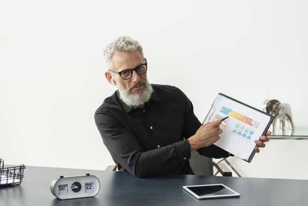 白发家里的老人在笔记本上展示图表 桌上放着平板电脑老年人老室内