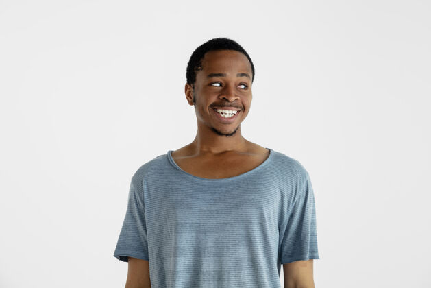 非洲美丽的男性半身像隔离在白色的墙上年轻情绪化的非洲裔美国人在蓝色衬衫面部表情 人类的情感 广告概念微笑 看着身边胡须肖像广告
