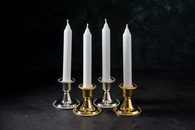 金金色和银色的白色蜡烛的正面图是黑色的烛台火焰白蜡烛