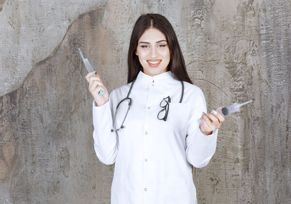 疾病面带微笑的年轻女医生拿着针剂看着前方年轻健康感染