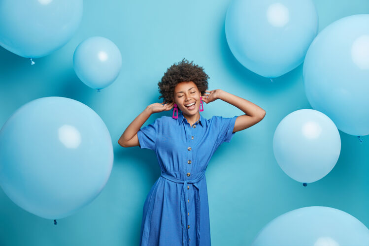 民族一个卷发的女人穿着时髦的衣服 喜欢音乐 在充气的气球周围摆出派对姿势 在蓝色的天空中有着与世隔绝的喜庆情绪乐趣女人氦