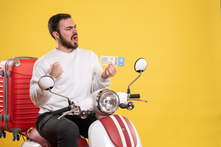 比赛旅游概念与惊讶的男子坐在摩托车上 手提箱上显示黄色的车票摩托车惊讶的男人人
