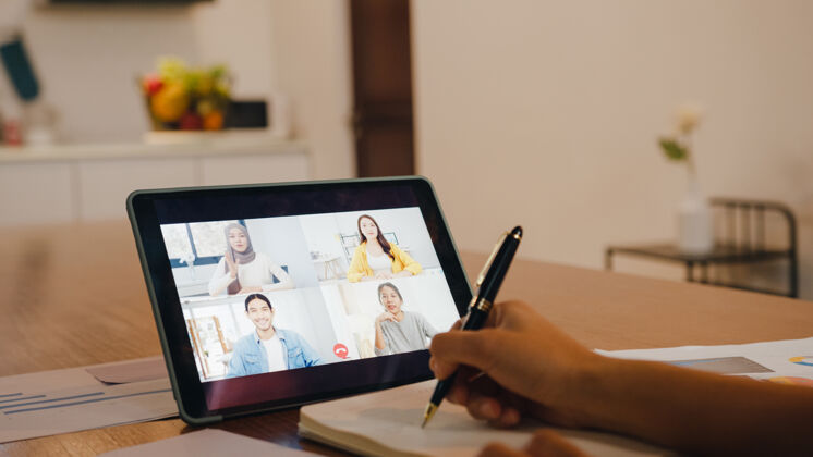 企业家亚洲女商人使用数字平板电脑通过视频电话与同事讨论计划头脑风暴在线会议 同时在家中厨房远程工作商务厨房隔离