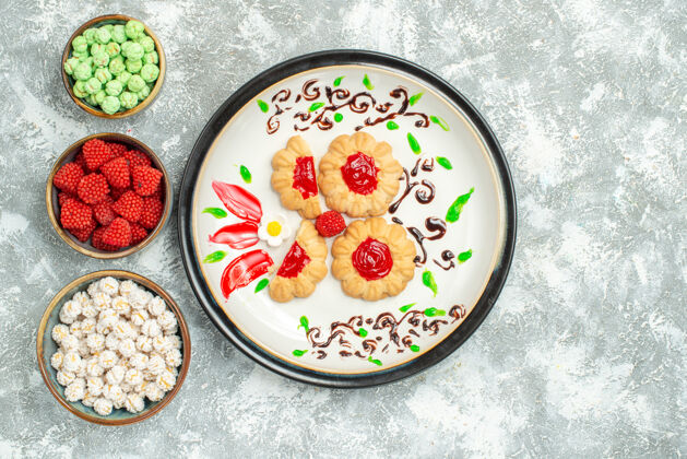 膳食俯瞰美味的饼干与红色果冻和糖果的白色背景饼干蛋糕饼干甜茶陶瓷器皿视图晚餐
