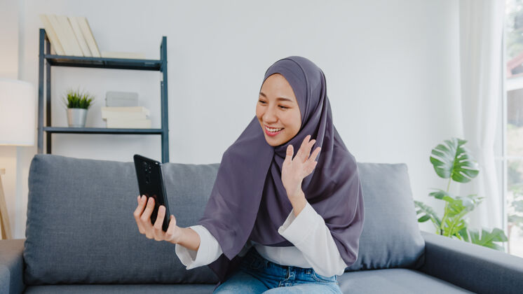 住宅女士戴着头巾 在家里用电话视频通话和夫妇交谈视频通话青少年阿拉伯语