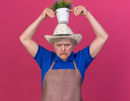 老人恼怒的上了年纪的女园丁戴着园艺帽 头顶着花盆帽子烦戴