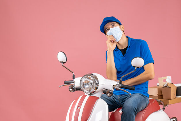 男俯视图：戴着医用面罩 戴着帽子的快递员坐在滑板车上 用粉彩桃子传递订单桃医疗高尔夫