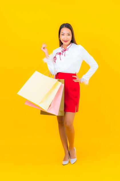 促销一位年轻漂亮的亚洲女士 手拿购物袋 信用卡 黄色欢呼付款魅力