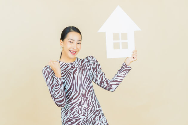 房地产肖像美丽的亚洲年轻女子与房子或家庭纸标志米色代理销售投资