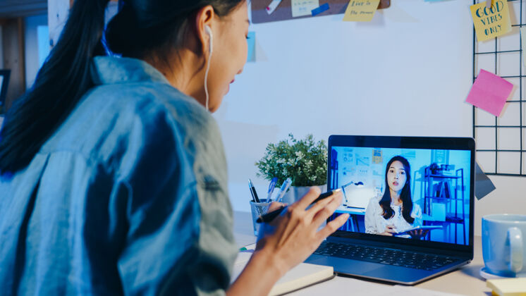 笔记本电脑亚洲女商人使用笔记本电脑在客厅视频电话会议上与同事讨论计划远程工作加班