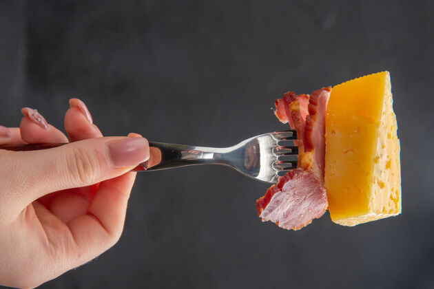 刷子手拿叉子美味香肠和奶酪片在黑暗的背景食物深色镜头