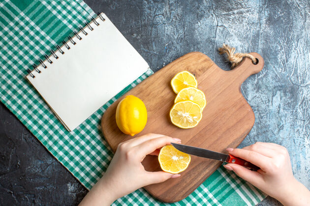 木材上图是一只手在木制砧板上切碎新鲜柠檬 在绿色的条布上做笔记本深色可食用水果毛巾