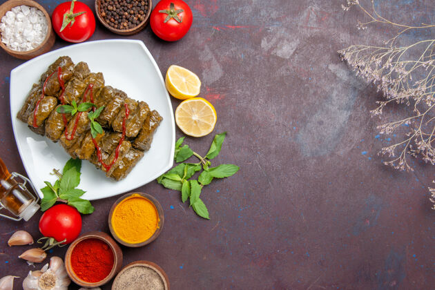 晚餐俯瞰美味的叶杜尔玛与不同的调味品和番茄对黑暗的背景肉菜叶食品晚餐食物顶部调味品