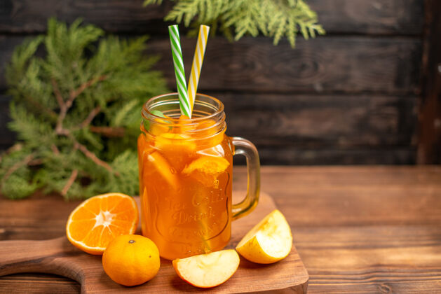 管前视图新鲜果汁在一个玻璃管和苹果和橘子在木制砧板上服务服务果汁壁板