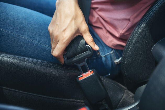 驾驶女士在车内手系安全带 剪下一张女士坐在车内并系上安全带的照片 安全驾驶理念成人安全紧固件