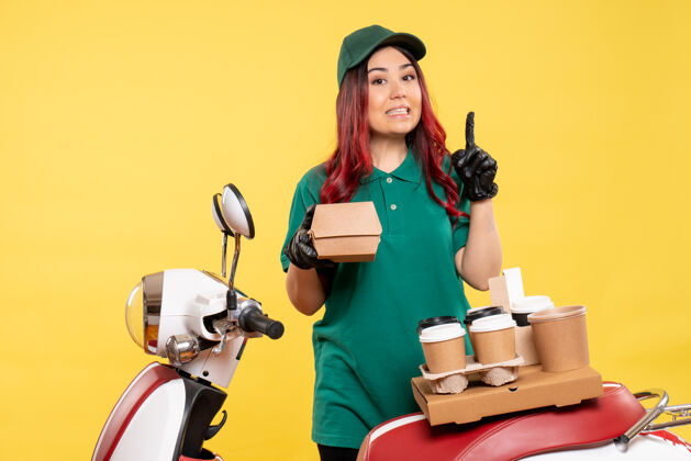 服务年轻的女快递员用黄色的咖啡和食品包裹送货送货包装咖啡
