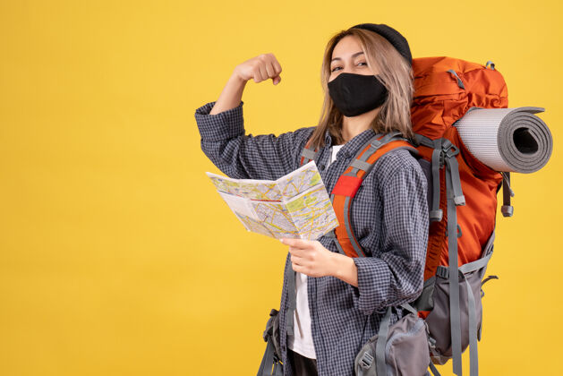 男人带着黑色面具和背包的旅行女孩拿着显示手臂肌肉的地图肌肉面具表演