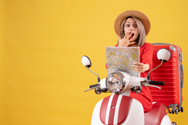 成人骑着轻便摩托车的漂亮女孩拿着红色手提箱拿着地图坐着摩托车地图
