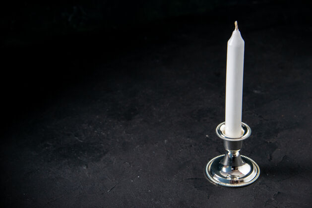 打蜡黑墙上白色长蜡烛的正面图光明黑色蜡烛