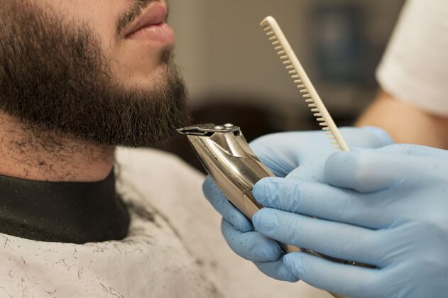 乳胶手套在理发店理胡子的年轻人理发师专业理发师
