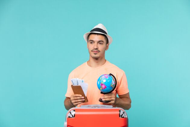 地球仪正面图男性在度假时拿着小地球仪和蓝色的门票举行假期旅行