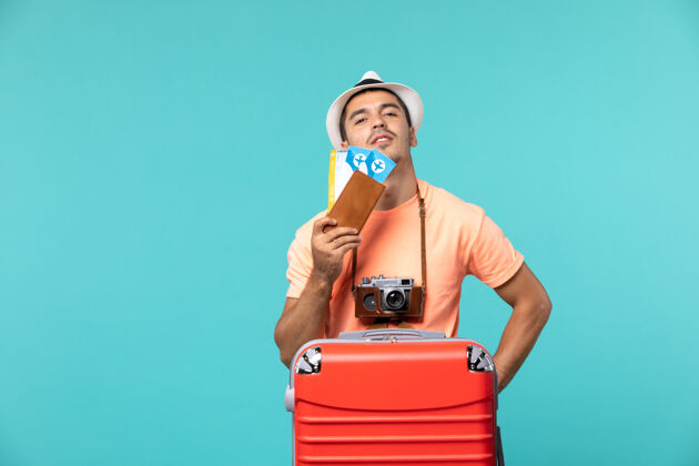 人正面图男性在度假时拿着他的机票在蓝色地板上旅行度假旅行飞机旅行肖像航程男人